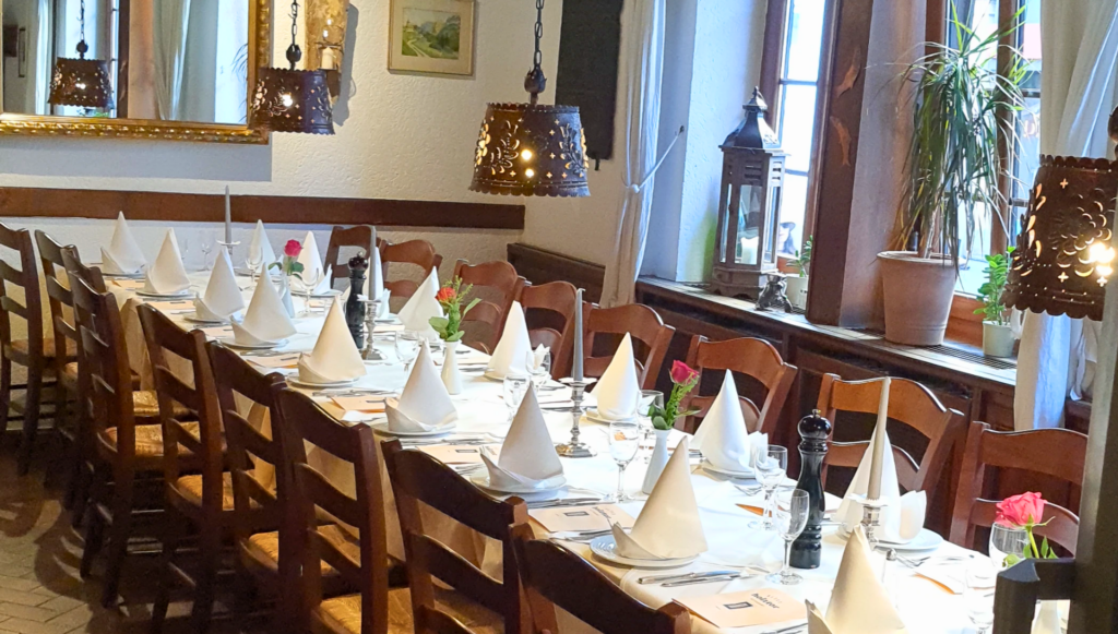 Langer Speisetisch festlich gedeckt mit weißen Tischdecken, eleganten Gläsern und frischen Blumen für ein besonderes Event im Restaurant "Altes Holztor" in Eltville am Rhein.